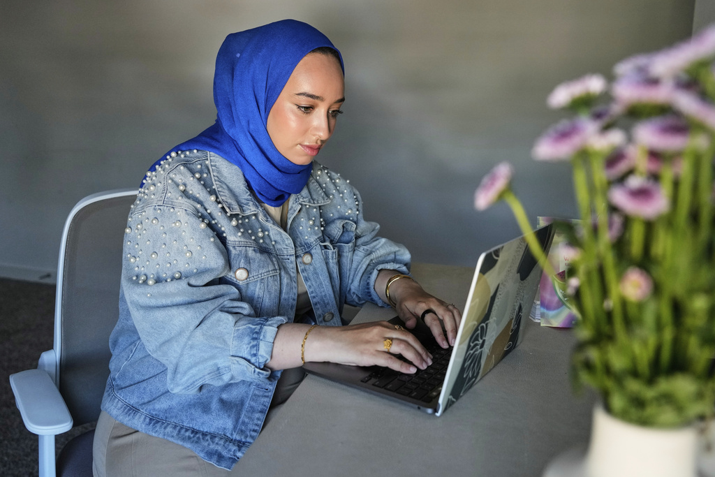 Hoda Abrahim, founder and CEO of Love, Inshallah, a matchmaker featured on the series "Muslim Matchmaker," on Hulu, works on her computer at her home on Monday, Aug. 11, 2025, in Conroe, Texas. (AP Photo/Ashley Landis)