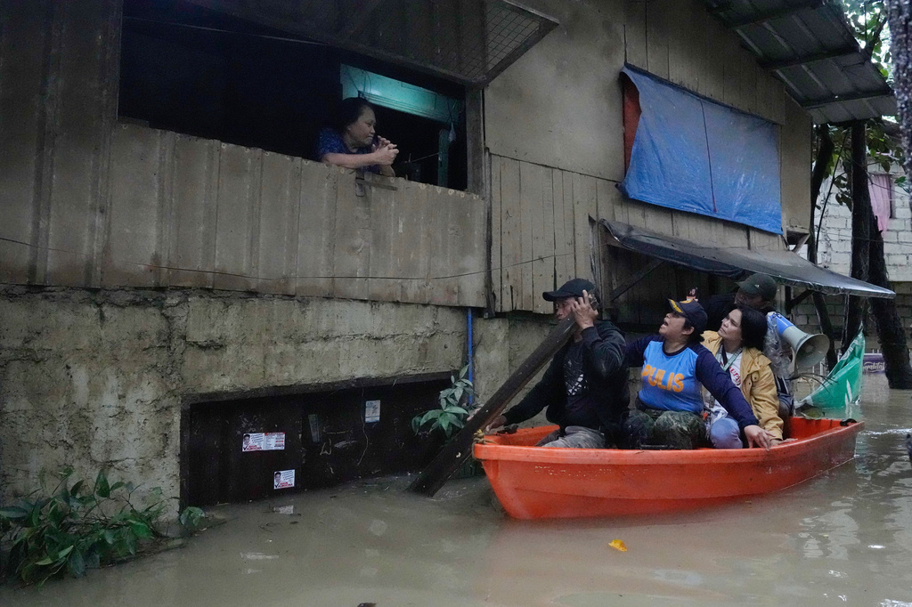 Police Lt. Col. Rowena Amata, second from left, and village officials, on boat, remind a resident to evacuate to higher grounds as floodwaters caused by heavy seasonal monsoon rains inundate a village at Bagong Silangan in Quezon city, Metro Manila, Philippines Monday, Aug. 10, 2026. (AP Photo/Aaron Favila) CORRECTION: Corrects typo in location to Silangan, instead of Silagan