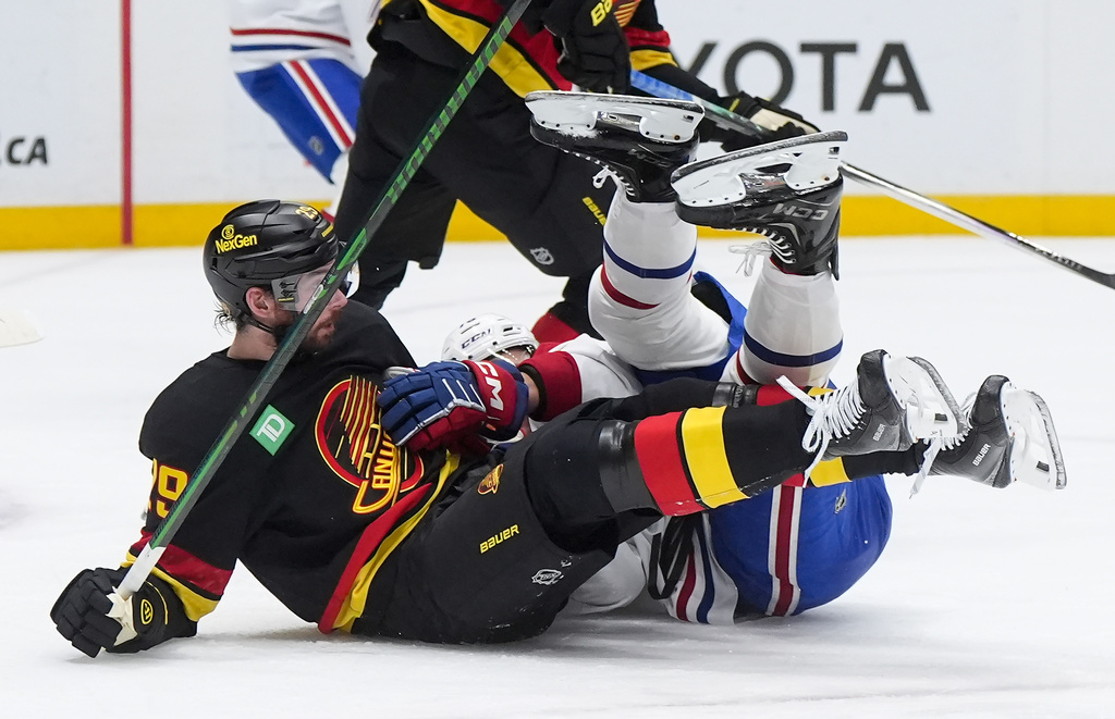 Vancouver Canucks' Marcus Pettersson, front left, and Montreal Canadiens' Zack Bolduc, right, fall to the ice after colliding during the second period of an NHL hockey game in Vancouver, British Columbia, Saturday, Oct. 25, 2025. (Darryl Dyck/The Canadian Press via AP)