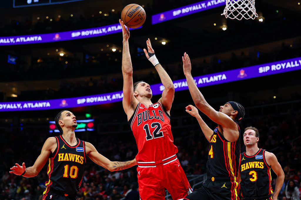 Chicago Bulls forward Zach Collins (12) shoots over Atlanta Hawks forward Asa Newell, right, during the first half of an NBA basketball game, Sunday, Dec. 21, 2025, in Atlanta. (AP Photo/Colin Hubbard)