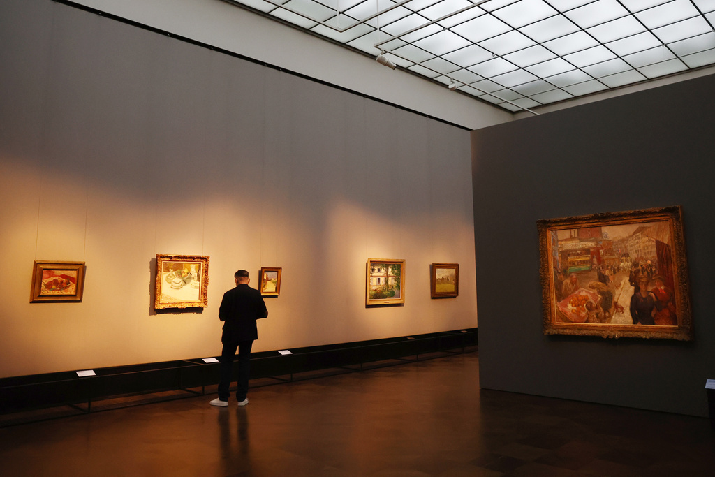 A visitor looks at a paintings with Pierre Bonnard's "Place Clichy" on the right, during a press preview of the exhibition "The Scharf Collection: Goya – Monet – Cezanne – Bonnard – Grosse" at the Alte Nationalgalerie museum in Berlin, Wednesday, Oct. 22, 2025. (AP Photo/Maryam Majd)