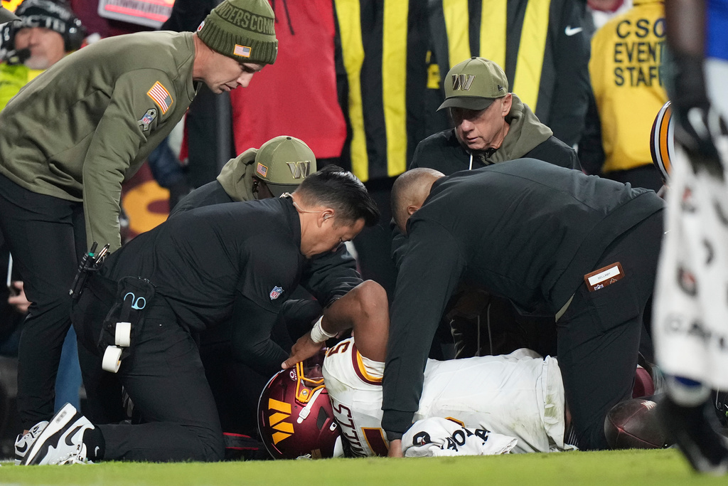 Washington Commanders quarterback Jayden Daniels (5) lays on the ground and is attended to by members of the Washington Commanders medical team after injuring his arm during the second half of an NFL football game, Sunday, Nov. 2, 2025, in Landover, Md. (AP Photo/Stephanie Scarbrough)