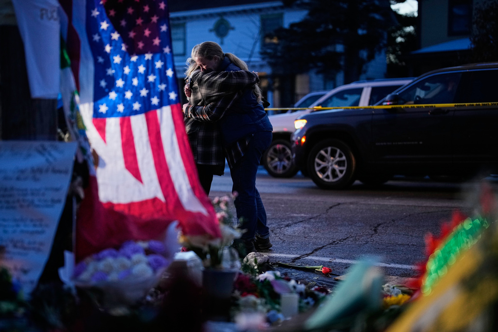 Monica Travis shares an embrace while visiting a makeshift memorial for Renee Good, who was fatally shot by an ICE officer last week, Monday, Jan. 12, 2026, in Minneapolis. (AP Photo/John Locher)