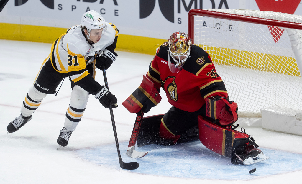 Pittsburgh Penguins center Ben Kindel (81) chases the puck as it deflects off Ottawa Senators goaltender Linus Ullmark (35) during first-period NHL hockey game action in Ottawa, Ontario, Thursday, March 26, 2026. (Adrian Wyld/The Canadian Press via AP)