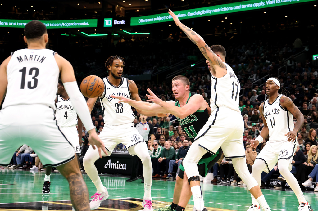 Boston Celtics guard Payton Pritchard (11) passes the ball past the Brooklyn Nets defense, including Nic Claxton (33), during the first half of an NBA Cup basketball game, Friday, Nov. 21, 2025, in Boston. (AP Photo/Mark Stockwell)