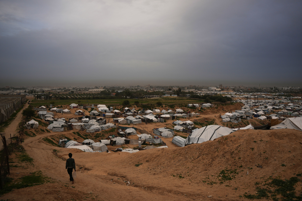 A child walks past tents housing displaced Palestinians in Deir al-Balah, central Gaza Strip, Sunday, Feb. 1, 2026. (AP Photo/Abdel Kareem Hana)
