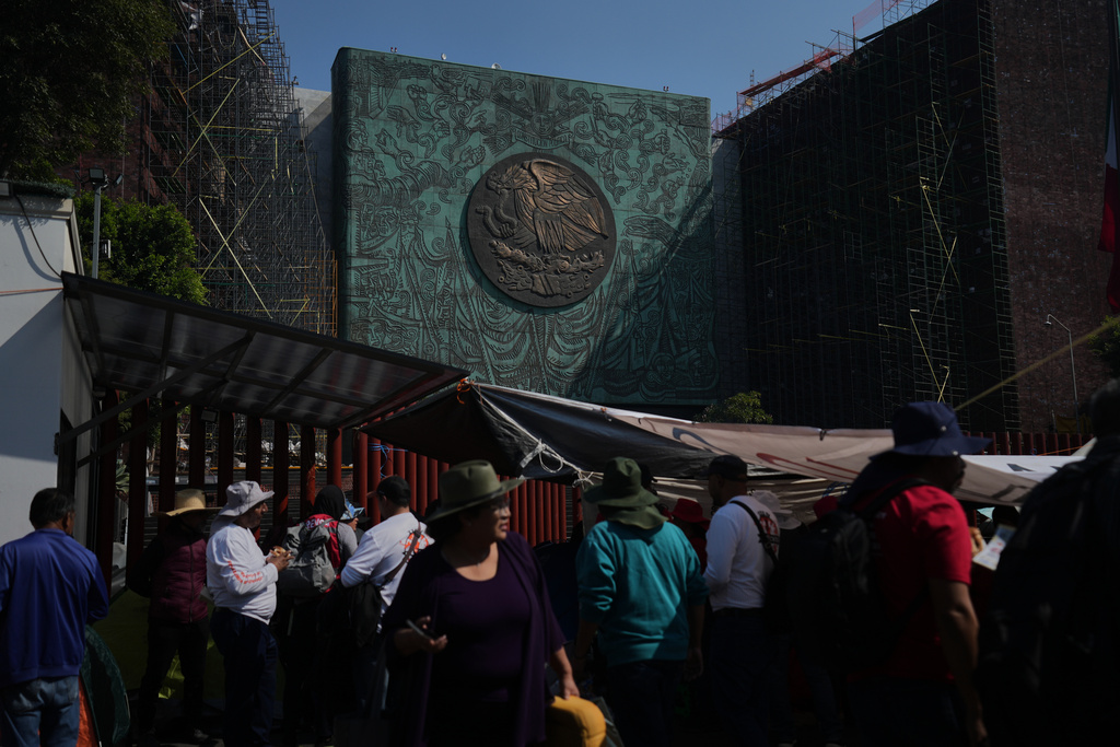 Protesters gather in front of the Legislative Palace of San Lazaro in Mexico City, where the Mexican coat of arms is visible on the building's façade, Thursday, Nov. 13, 2025. (AP Photo/Claudia Rosel)