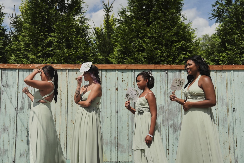 Bridesmaids Alyssa Gunning, from left, Eve Shepherd, Dakota-Jade Jones and Ndiah Jones use fans for shade and to keep cool during bridal pictures before a wedding Saturday, Aug. 23, 2025, in Newtown, Ohio. (AP Photo/Joshua A. Bickel)