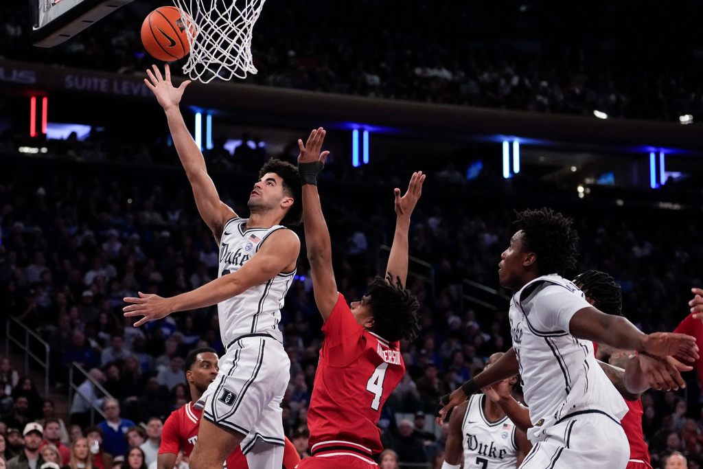 Duke guard Cayden Boozer, left, shoots over Texas Tech guard Christian Anderson (4) during the first half of an NCAA college basketball game, Saturday, Dec. 20, 2025, in New York. (AP Photo/Yuki Iwamura)