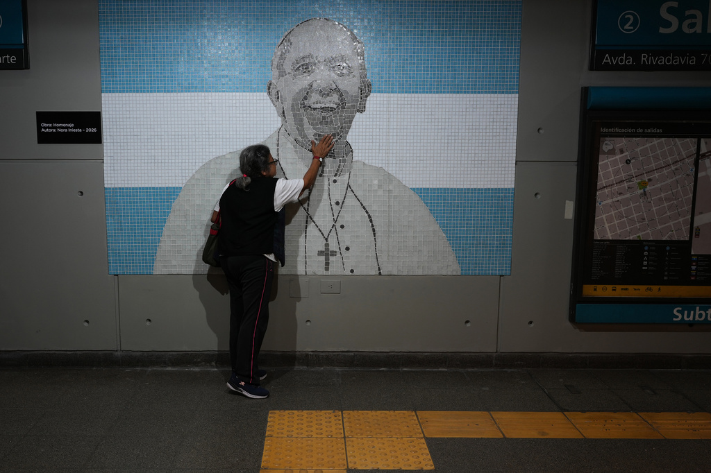 A commuter touches a mosaic of the late Pope Francis in a subway station on the one-year anniversary of his passing, in Buenos Aires, Argentina, Tuesday, April 21, 2026. (AP Photo/Rodrigo Abd)