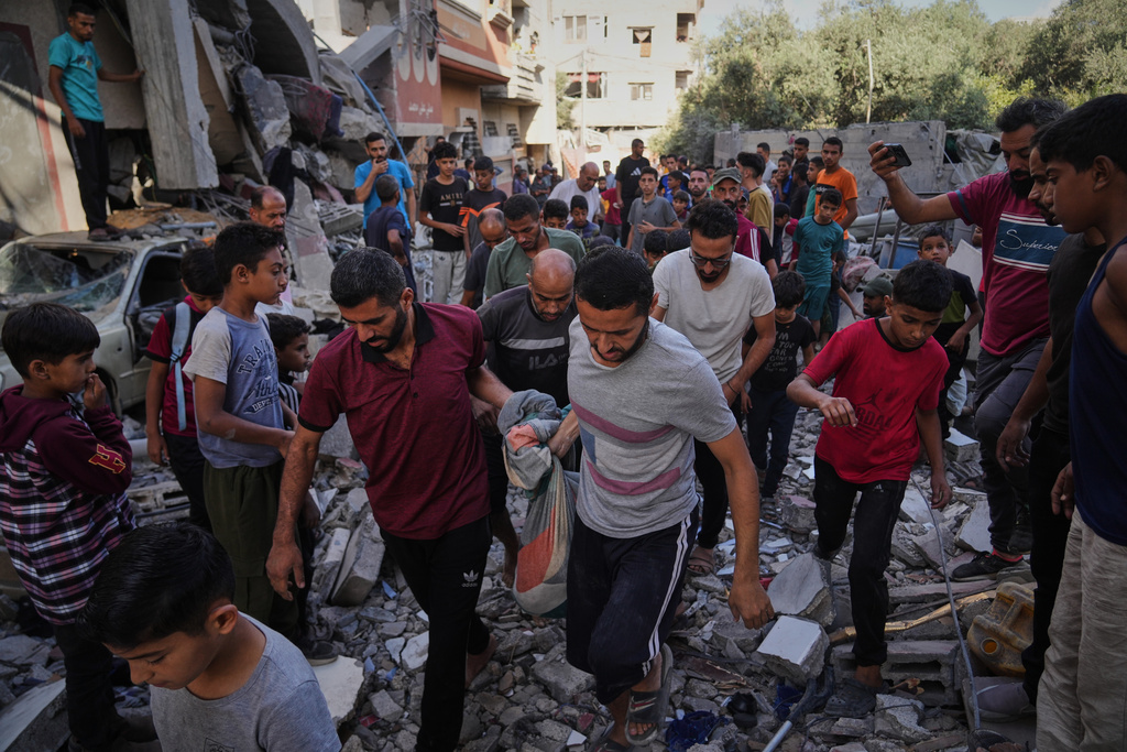 Palestinians carry the body of Hassan Nasr, 12, from the rubble of his relatives home, which was hit by an Israeli military strike in Zawaida, central Gaza Strip, Thursday, Sept. 25, 2025. (AP Photo/Abdel Kareem Hana)