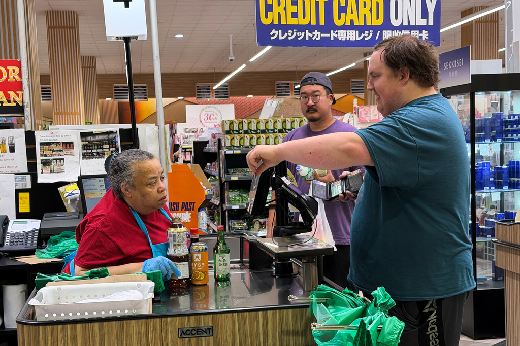 An employee checks a customer's identification card before checking out alcohol at a cash register in a grocery store in Arlington Heights, Ill., Monday, July 6, 2026. (AP Photo/Nam Y. Huh)
