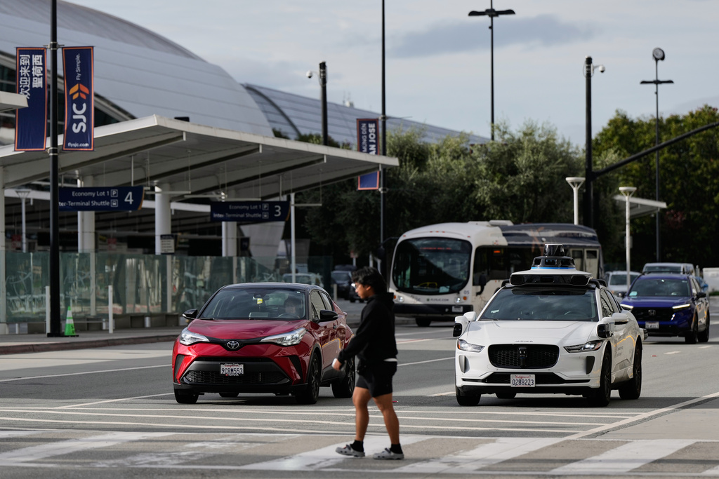 A Waymo vehicle waits as a pedestrian walks on a crosswalk at the San Jose Mineta International Airport, Wednesday, Nov. 12, 2025, in San Jose, Calif. (AP Photo/Godofredo A. Vásquez)