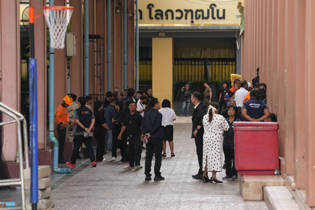 First responders and others stand inside after a shooting at the Debsirin Nonthaburi School in Thailand's Nonthaburi province, Friday, Aug. 7, 2026. (AP Photo/Sakchai Lalit)