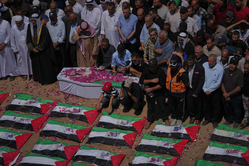 Mourners gather around the flag-draped bodies of members of the Hassayna and Abu Sharia families, killed in an Israeli strike in 2023 and recently recovered from the rubble, during their funeral in Gaza City, Tuesday, Aug. 4, 2026. (AP Photo/Jehad Alshrafi)