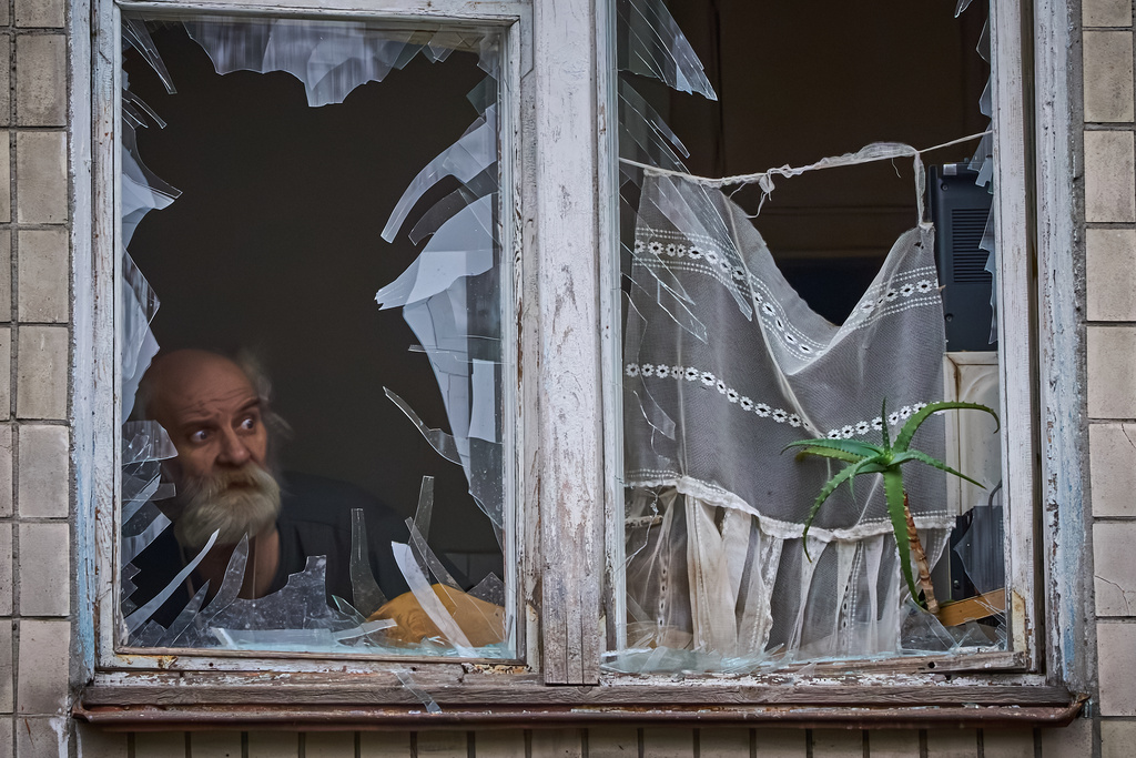 An elderly man looks out of his broken window as an apartment building was hit by a Russian drone during an aerial attack in Kyiv, Ukraine, Tuesday, Dec. 23, 2025. (AP Photo/Efrem Lukatsky)