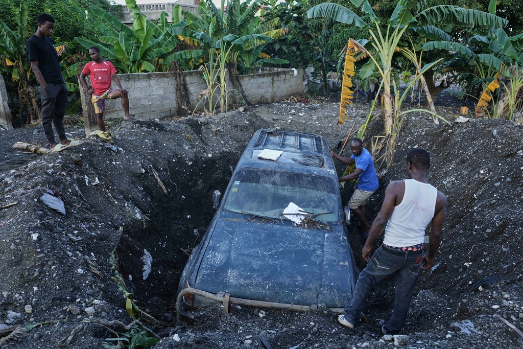 Residents work to remove a partially buried vehicle in the aftermath of Hurricane Melissa in Petit-Goave, Haiti, Nov. 6, 2025. (AP Photo/Odelyn Joseph)