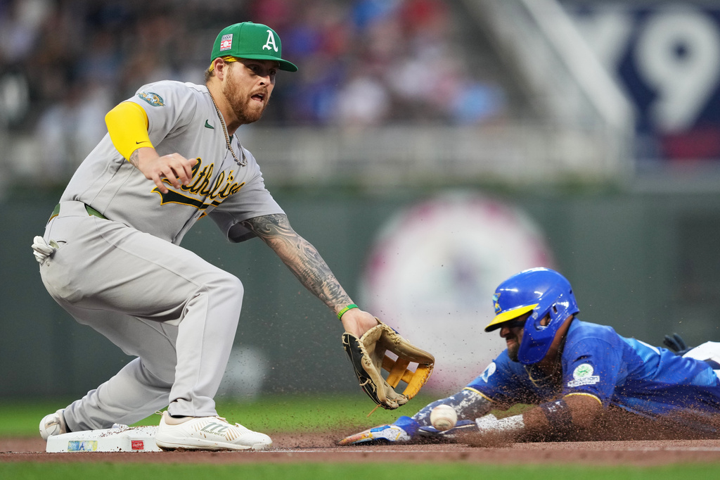 Athletics third baseman Tommy White, left, attempts to catch the ball while Minnesota Twins' Royce Lewis slides safely into third base during the fourth inning of a baseball game, Friday, July 24, 2026, in Minneapolis. (AP Photo/Ellen Schmidt)
