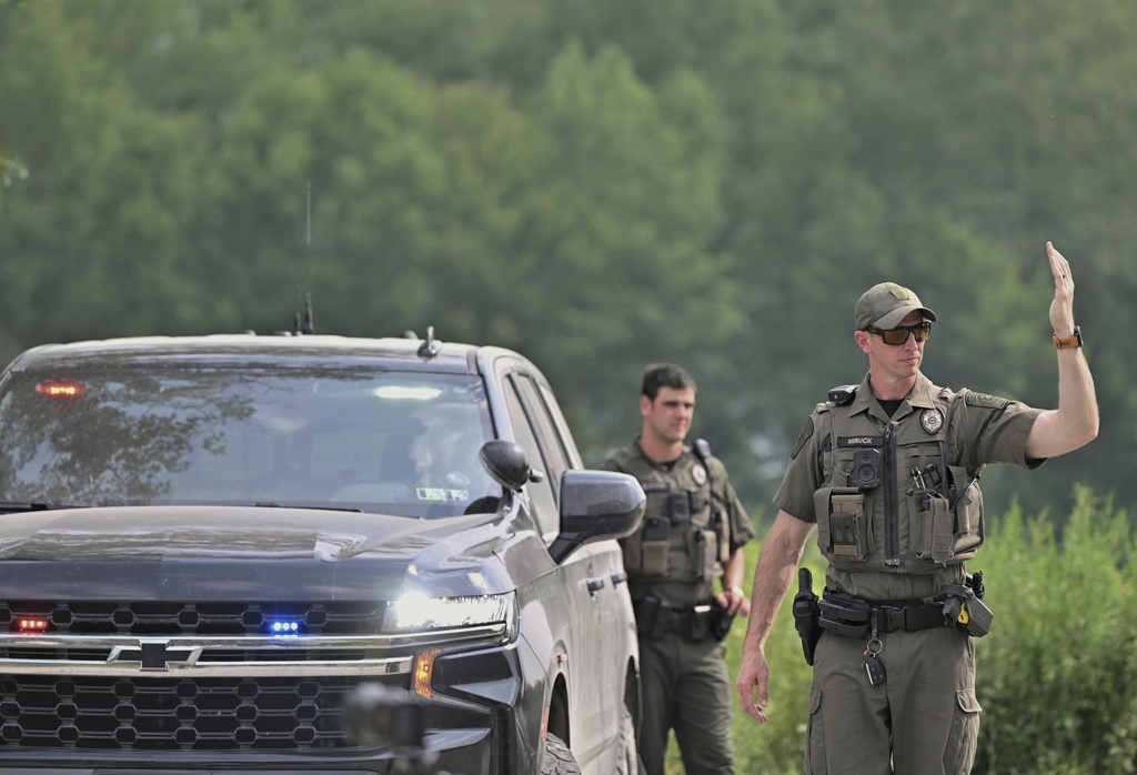 Police officers block the street leading to where two Pennsylvania state troopers were ambushed and shot Thursday, Aug. 7, 2025, near the village of Thompson in Susquehanna County, Pa. (AP Photo/Aimee Dilger)