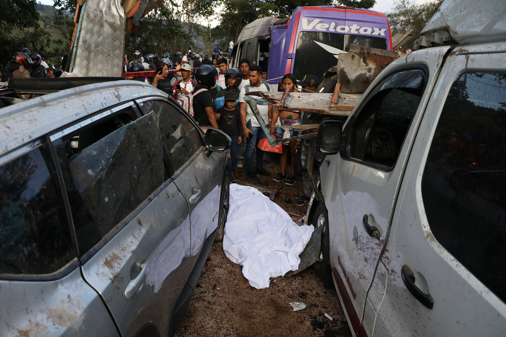 The covered body of a victim lies among vehicles damaged in an attack on the Pan-American Highway in Cajibio, Colombia, Saturday, April 25, 2026, where authorities said at least a dozen people were killed and blamed dissident groups of the former FARC rebels. (AP Photo/Santiago Saldarriaga)