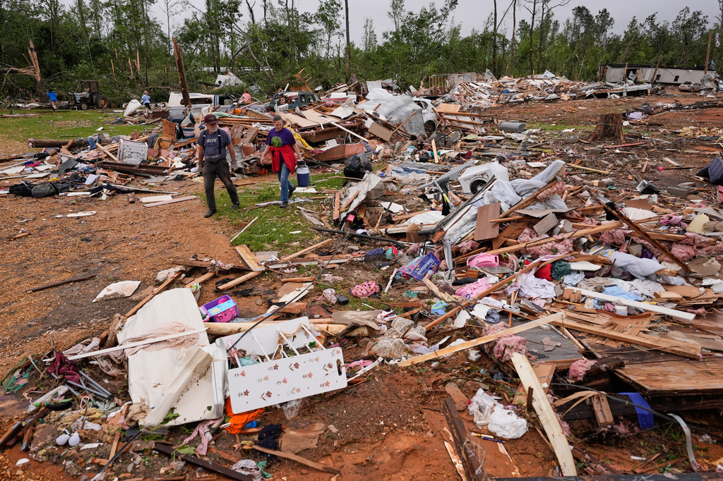 People walk among debris at Gene's Mobile Home Supply, a trailer park in Bogue Chitto, Miss., Thursday, May, 7, 2026, after a tornado cut across the state. (AP Photo/Gerald Herbert)
