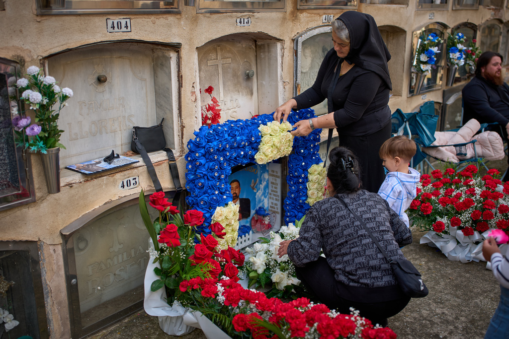 People place flowers on a grave during All Saints' Day, a Catholic holiday to honor saints and remember deceased relatives, at a municipal cemetery in Barcelona, Spain, Saturday, Nov. 1, 2025. (AP Photo/Emilio Morenatti)