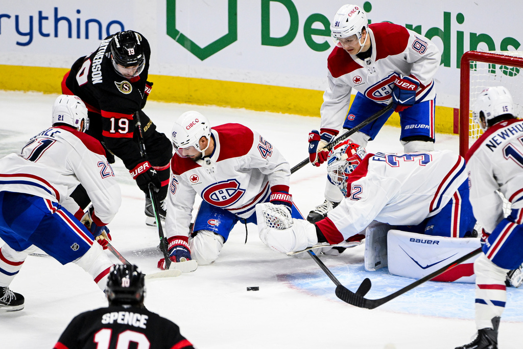 Montreal Canadiens goaltender Jacob Fowler (32) reaches out for the puck as Ottawa Senators' Drake Batherson (19) looks for a shot on goal opportunity during the third period of an NHL hockey game in Ottawa, Ontario, Wednesday, March 11, 2026. (Spencer Colby/The Canadian Press via AP)