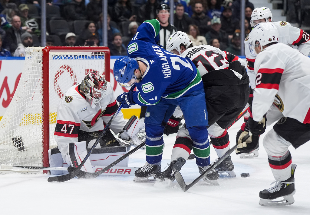Vancouver Canucks' Nils Hoglander (21) looks for the puck after being stopped by Ottawa Senators goalie James Reimer (47) as Thomas Chabot (72) defends during the third period of an NHL hockey game, in Vancouver, on Monday, March 9, 2026. (Darryl Dyck/The Canadian Press via AP)