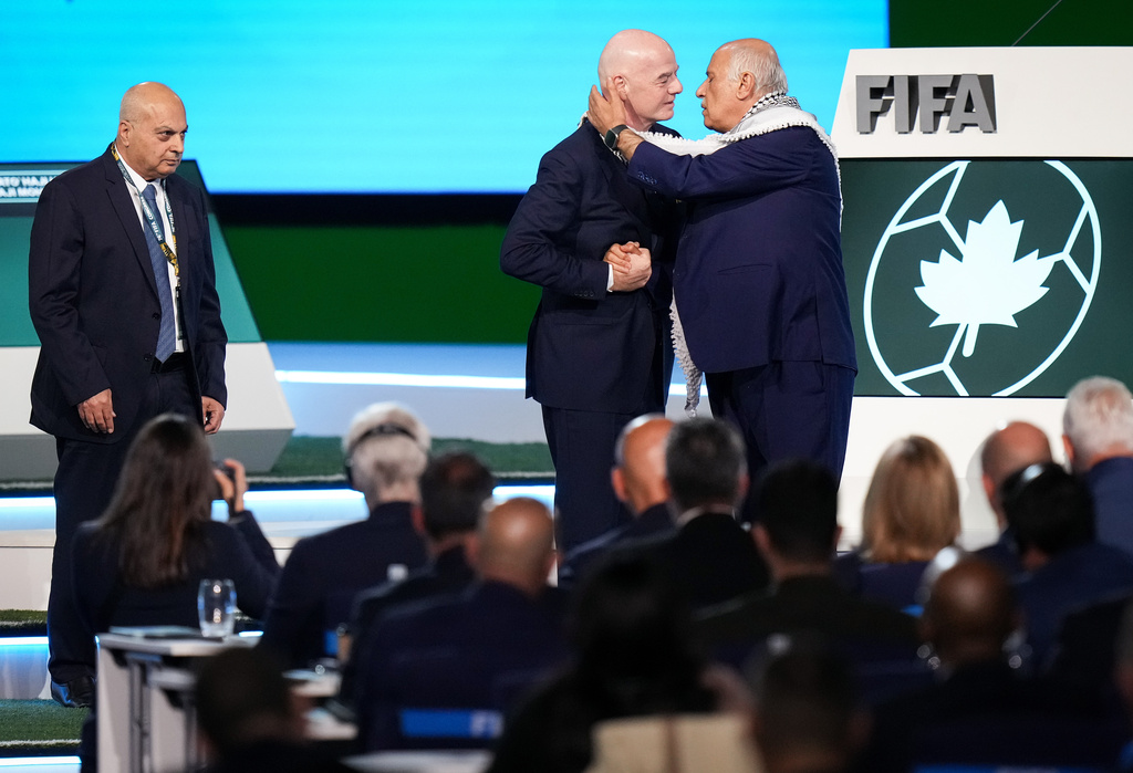 Palestinian Football Association President Jibril Rajoub, right, reaches to kiss FIFA President Gianni Infantino on the cheek after speaking as Israel Football Association Vice-President Basim Sheikh Suliman, left, watches during the 76th FIFA Congress in Vancouver, British Columbia, Thursday, April 30, 2026. (Darryl Dyck/The Canadian Press via AP)