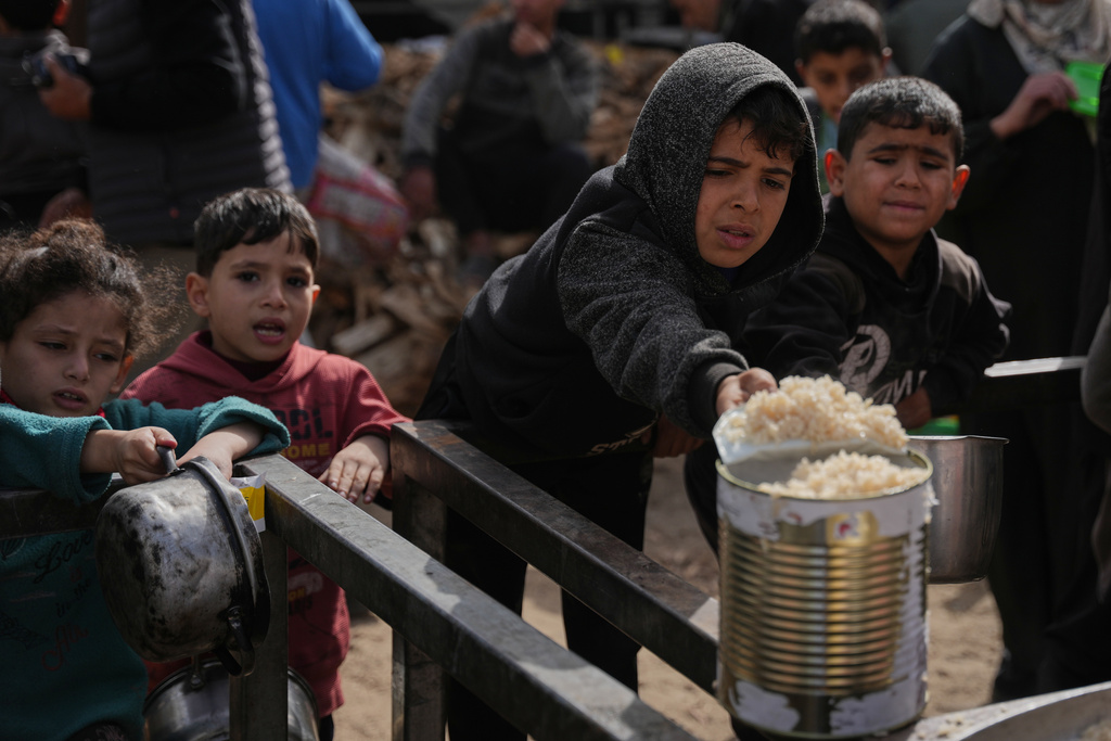 Palestinian children receive donated food at a community kitchen in Nuseirat, in central Gaza Strip, Saturday, Jan. 24, 2026. (AP Photo/Abdel Kareem Hana)