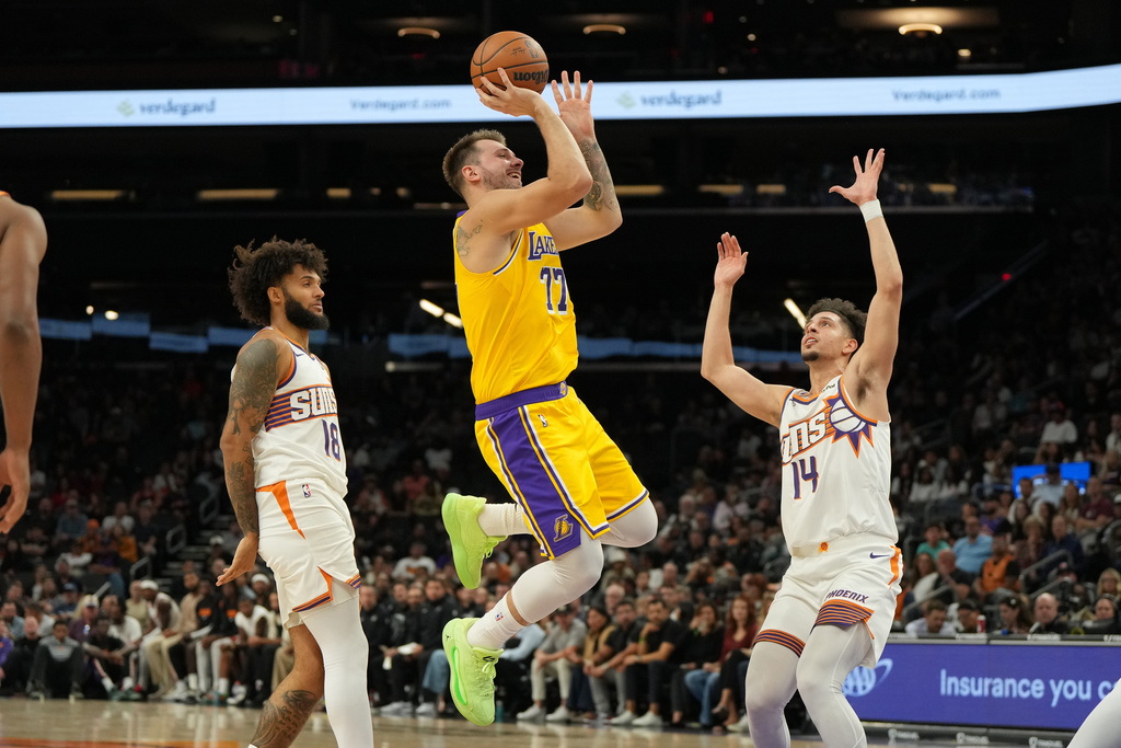 Los Angeles Lakers forward/guard Luka Dončić (77) shoots between Phoenix Suns Isaiah Livers and and Koby Brea (14) during the first half of an NBA basketball game, Tuesday, Oct. 14, 2025, in Phoenix. (AP Photo/Rick Scuteri)