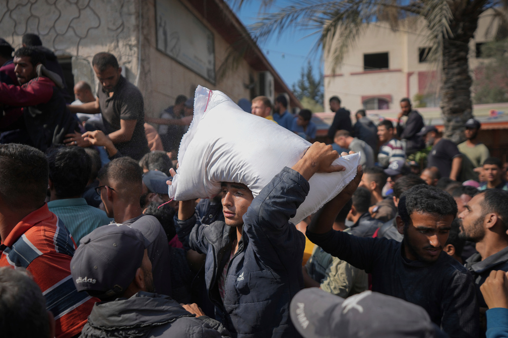 FILE - Palestinians gather to receive bags of flour distributed by UNRWA, the U.N. agency helping Palestinian refugees, in Deir al Balah, central Gaza Strip, Nov. 2, 2024. (AP Photo/Abdel Kareem Hana, File)
