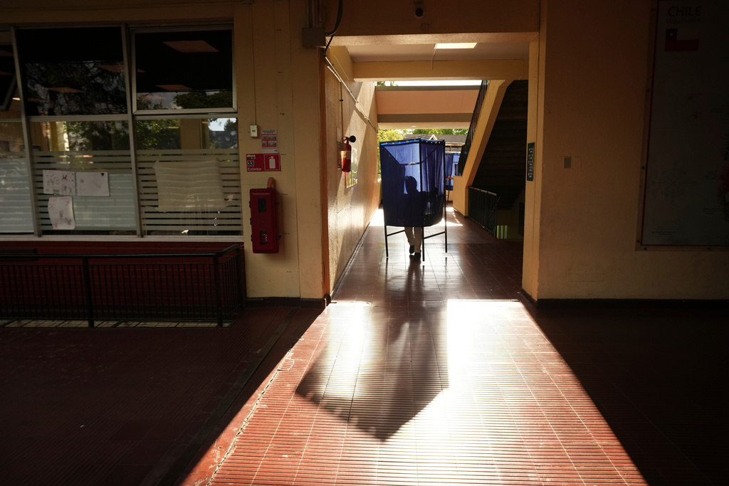 A worker carries away a voting booth after polls closed during general elections in Santiago, Chile, Sunday, Nov. 16, 2025. (AP Photo/Esteban Felix)