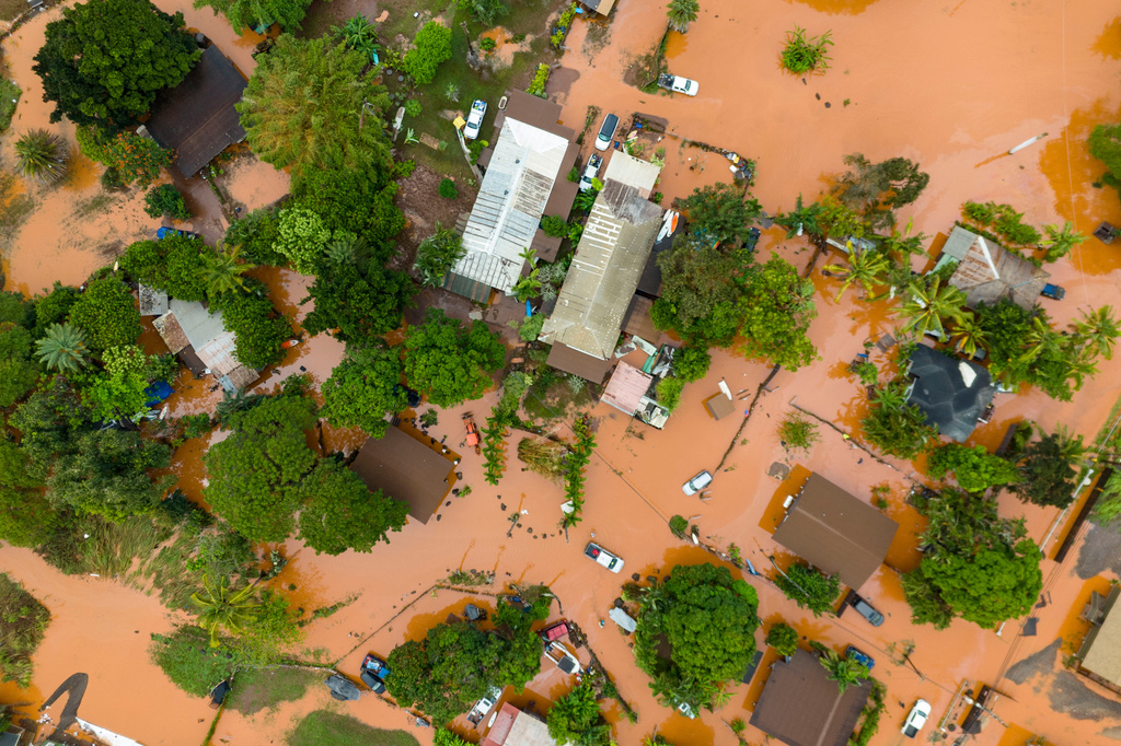 An aerial view of homes surrounded by floodwaters in Waialua, Hawaii, Friday, March 20, 2026. (AP Photo/Mengshin Lin)