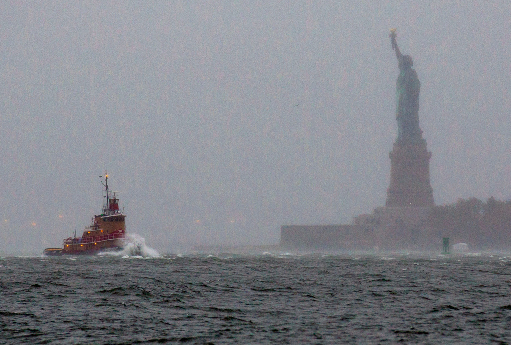 FILE - Waves crash over the bow of a tug boat as it passes near the Statue of Liberty in New York as rough water as the result of Hurricane Sandy churns the waters of New York Harbor, Oct. 29, 2012. (AP Photo/Craig Ruttle, File)