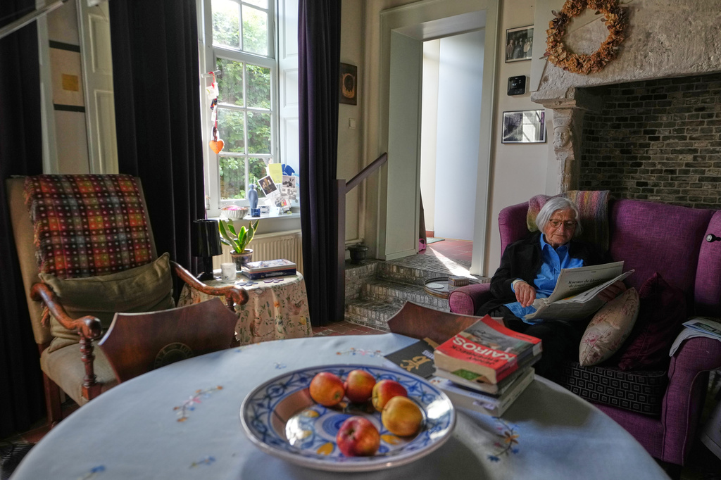 Resident Brigitte Beernaert reads a newspaper inside a house of the Beguinage Ten Wijngaerde in Bruges, Belgium, Wednesday, April 15, 2026. (AP Photo/Virginia Mayo)