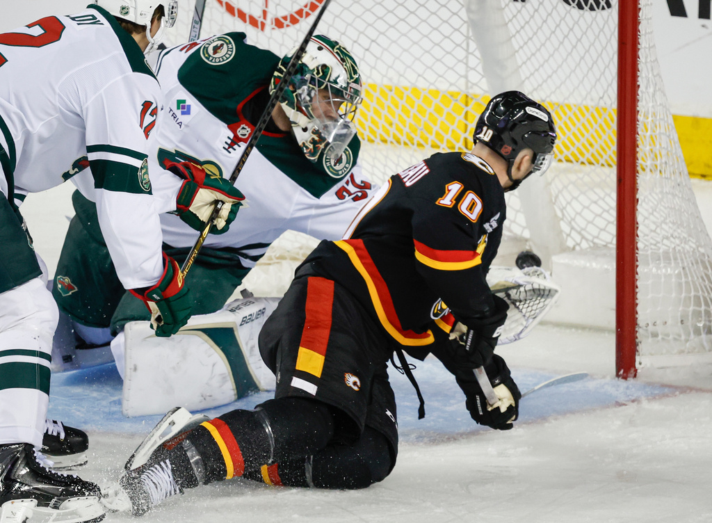 Minnesota Wild goalie Filip Gustavsson, left, is scored on by Calgary Flames' Jonathan Huberdeau during second period NHL hockey action in Calgary on Thursday, Dec. 4, 2025. (Jeff McIntosh/The Canadian Press via AP)