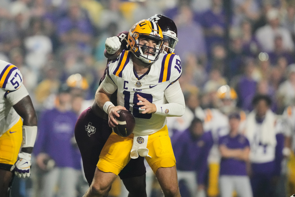 CORRECTS TO TEXAS A&M DEFENSIVE END CASHIUS HOWELL NOT CORNERBACK JULIO HUMPHREY - LSU quarterback Garrett Nussmeier (18) is sacked by Texas A&M defensive end Cashius Howell, back, in the first half of an NCAA college football game, Saturday, Oct. 25, 2025 in Baton Rouge, La. (AP Photo/Gerald Herbert)