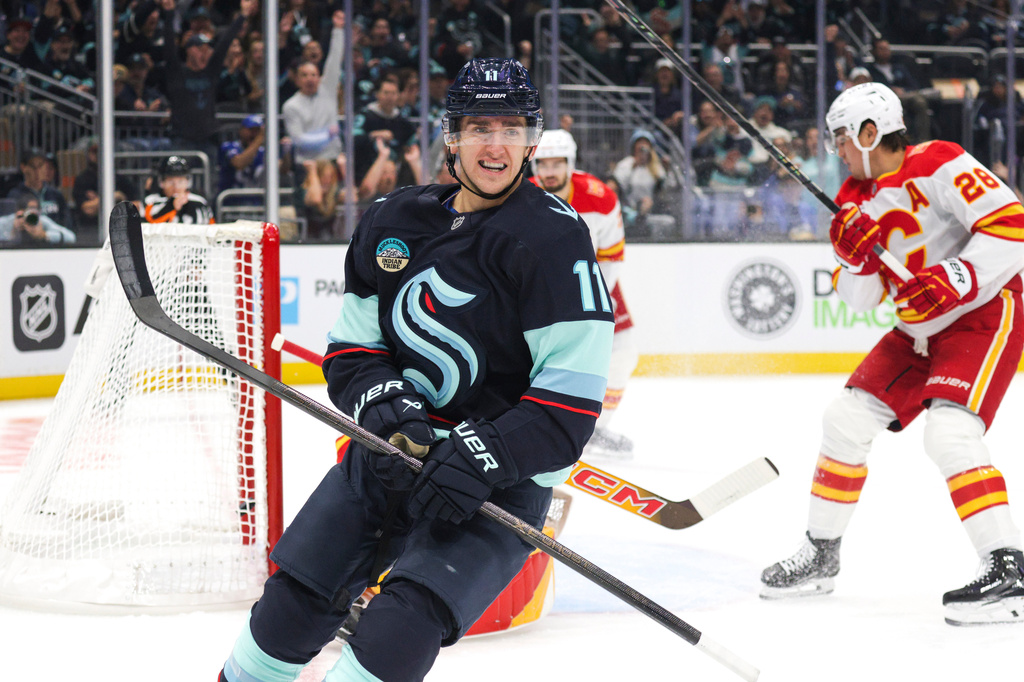 Seattle Kraken right wing Mackie Samoskevich (11) reacts after scoring as Calgary Flames defenseman Zach Whitecloud (28) skates off during the first period of an NHL hockey game Sunday, Oct. 4, 2026, in Seattle. (AP Photo/Jason Redmond)
