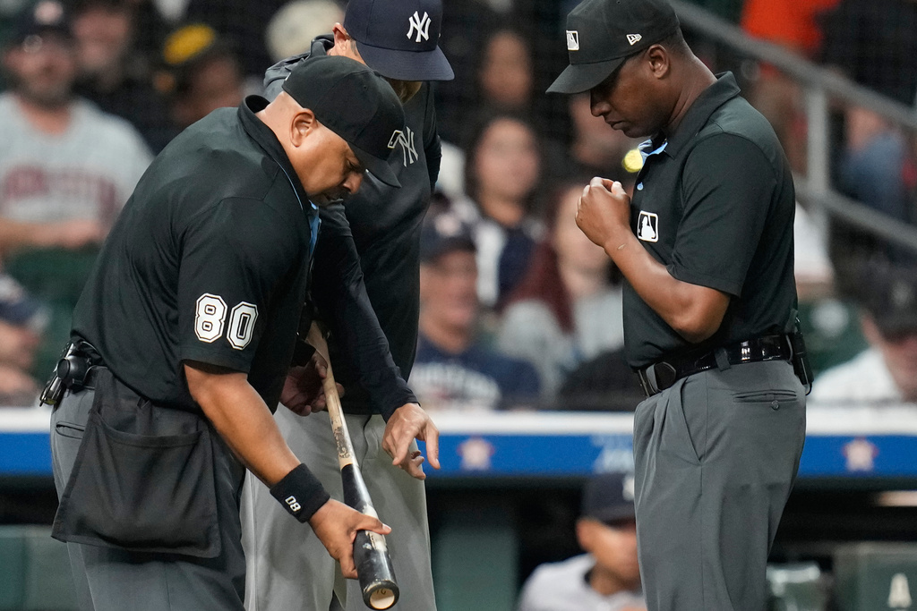 New York Yankees manager Aaron Boone, center, points at Houston Astros' Taylor Trammell's bat held home plate umpire Adrian Johnson, left, as umpire Ramon De Jesus, right, looks on during the ninth inning of a baseball game Thursday, Sept. 4, 2025, in Houston. (AP Photo/Karen Warren)