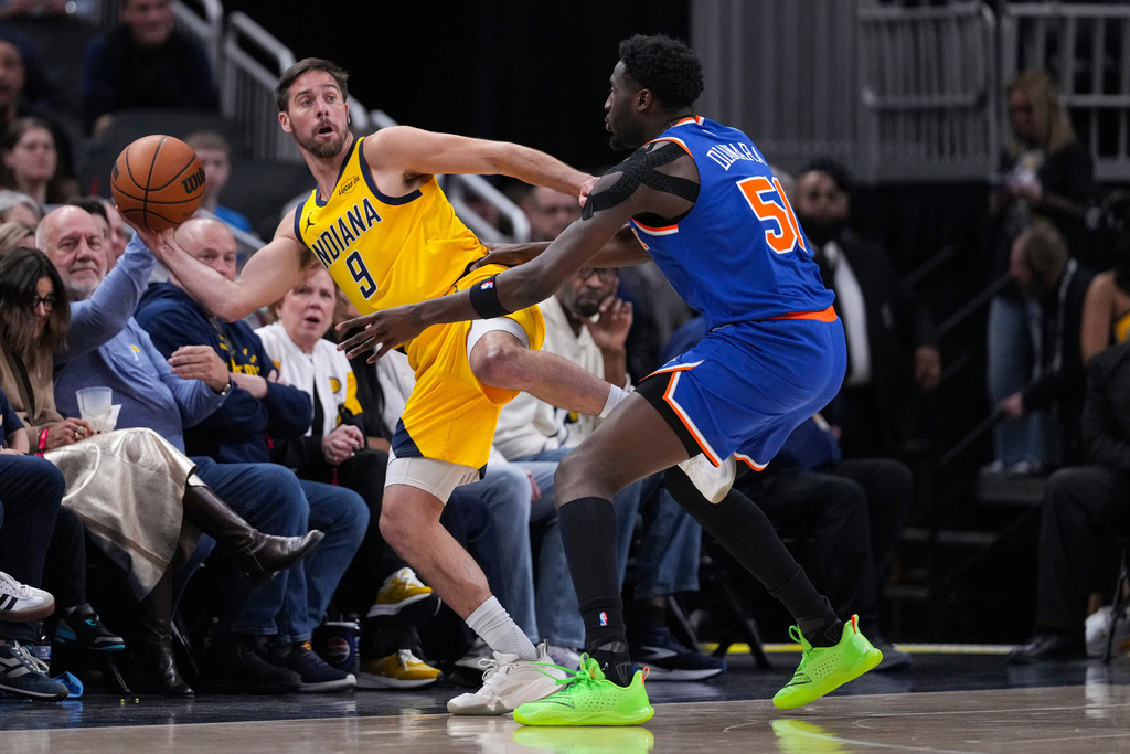 Indiana Pacers guard T.J. McConnell (9) makes a save in front of New York Knicks forward Mohamed Diawara (51) during the first half of an NBA basketball game in Indianapolis, Friday, March 13, 2026. (AP Photo/Michael Conroy)