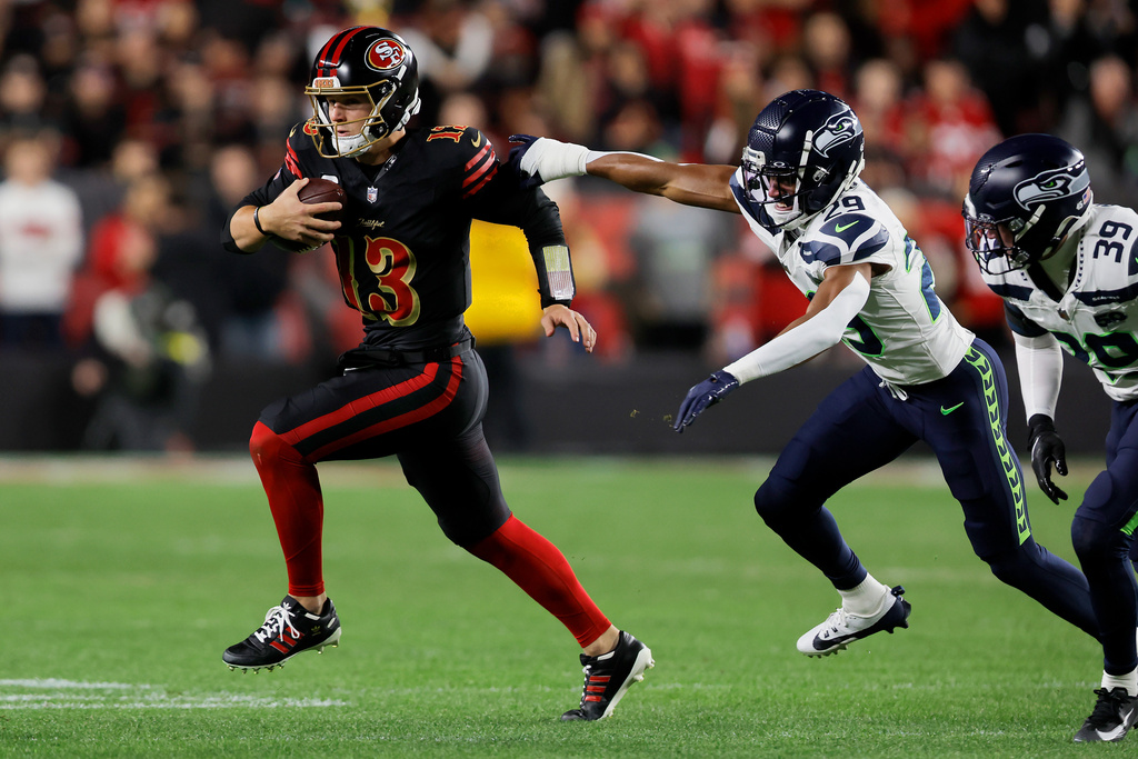San Francisco 49ers Brock Purdy (13) scrambles away from Seattle Seahawks Josh Jobe (29) and Ty Okada (39) during the first half of an NFL football game in Santa Clara, Calif., Saturday, Jan. 3, 2026. (Carlos Avila Gonzalez/San Francisco Chronicle via AP)