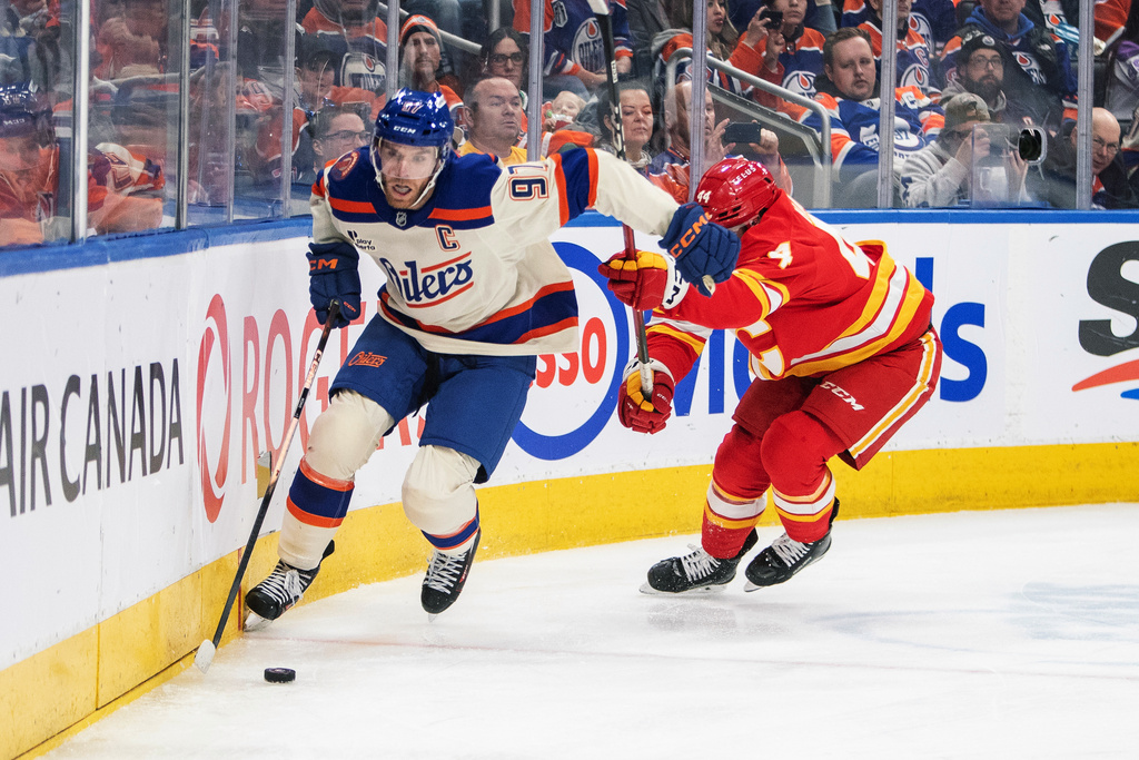 Calgary Flames' Joel Hanley (44) chases Edmonton Oilers' Connor McDavid (97) during second period NHL action in Edmonton, Alberta, Tuesday, Dec. 23, 2025. (Amber Bracken/The Canadian Press via AP)