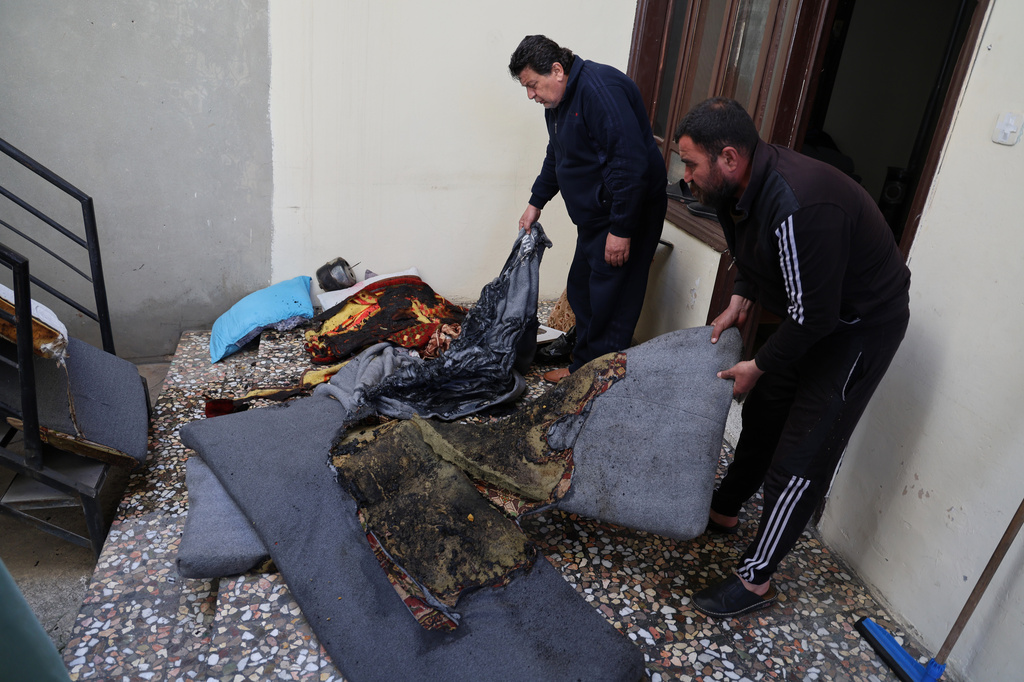 Men remove burned furniture inside a damaged home following overnight violence in the predominantly Christian town of Al-Suqaylabiyah, west of Hama, Syria, Saturday, March 28, 2026. (AP Photo/Omar Albam)