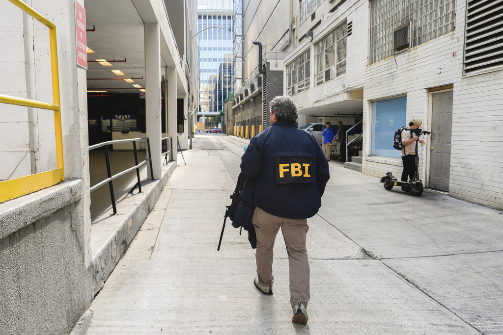 An FBI agent walks to the front entrance of ex-Trump national security adviser John Bolton's Washington office, Friday, Aug 22, 2025. (AP Photo/Julia Demaree Nikhinson)