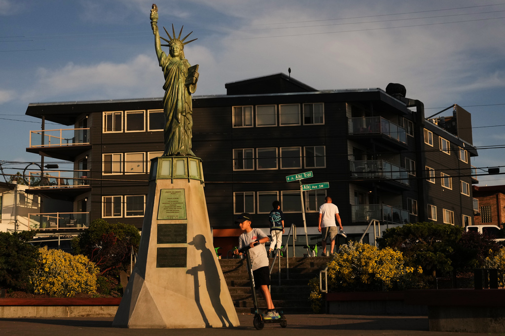 A child rides a scooter in circles around a replica of the Statue of Liberty, installed in 1952 by the Boy Scouts of America, at Alki Beach Park in Seattle, Washington, Wednesday, June 24, 2026. (AP Photo/Lindsey Wasson)
