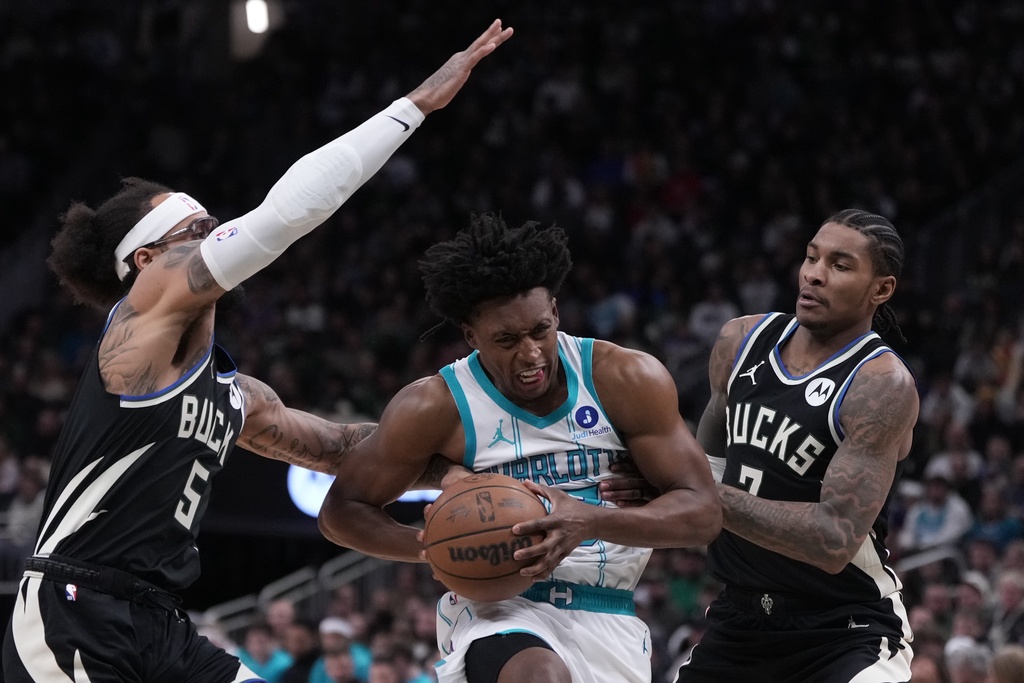 Charlotte Hornets guard Collin Sexton (8) drives between Milwaukee Bucks guard Kevin Porter Jr. (7) and guard Gary Trent Jr. (5) during the first half of an NBA basketball game Friday, Jan. 2, 2026, in Milwaukee. (AP Photo/Morry Gash)