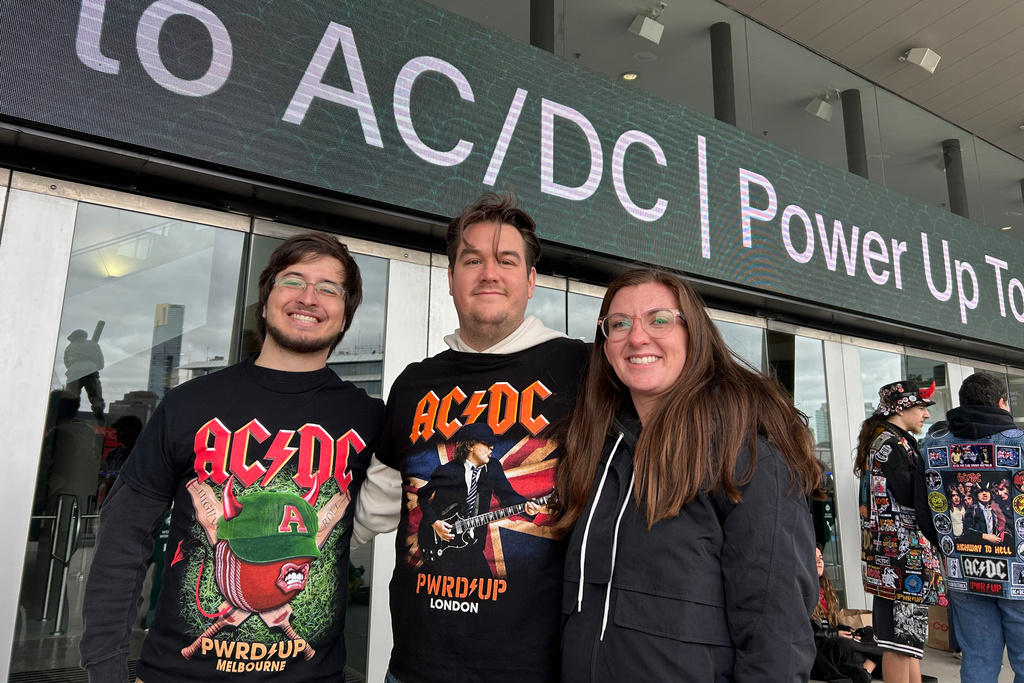 Keegan Kohler, left, Stephen Scott and Amber Thompson, right, wait outside a Melbourne, Australia, stadium on Wednesday, Nov. 12, 2025, hours before gates open for an AC/DC concert. (AP Photo/Rod McGuirk)