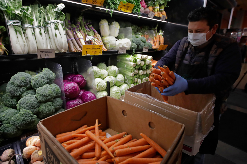FILE - A worker stocks produce before the opening of a market in San Francisco, March 27, 2020. (AP Photo/Ben Margot, File)