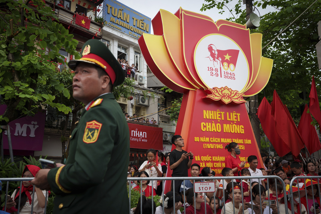 People wait for the final day of a military parade rehearsal for the 80th National Day celebration in Hanoi, Vietnam, Saturday, Aug. 30, 2025. (AP Photo/Vincent Thian)